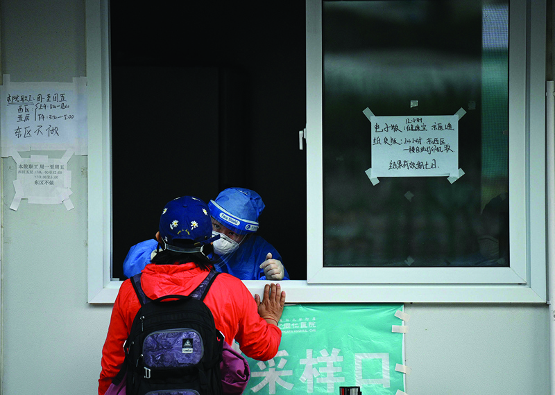 BEIJING: A health worker takes a swab sample from a woman to be tested for the COVID-19 coronavirus in Beijing yesterday. - AFPn