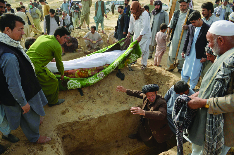 KUNDUZ: Relatives lower into a grave the body of a victim of suicide bomb attack on worshippers at a Shiite mosque, in which at least 55 people died, during the funeral at a graveyard in Kunduz yesterday. - AFP n