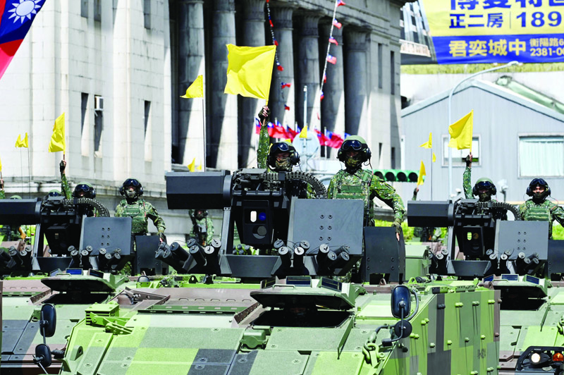 TAIPEI: Taiwanese soldiers raise flags on military vehicles during a national day parade in front of the Presidential Palace during in Taipei yesterday. - AFPn