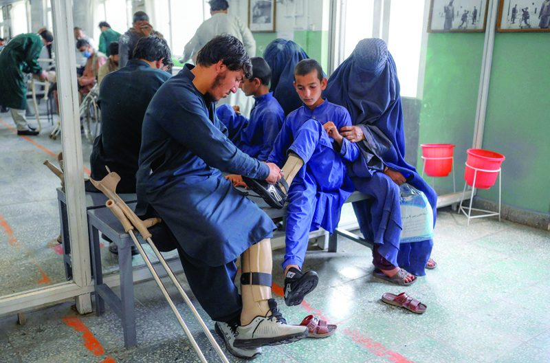 KABUL: A man helps a boy put on shoes on his new prosthetic leg at the International Committee of Red Cross Rehabilitation Centre in Kabul. - AFP n