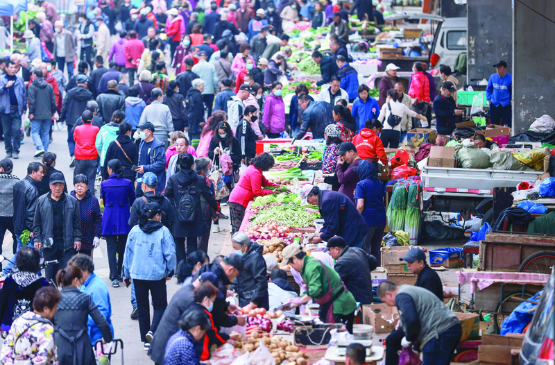 SHENYANG, China: People buy vegetables at a market in Shenyang in China's northeastern Liaoning province yesterday.-AFPn