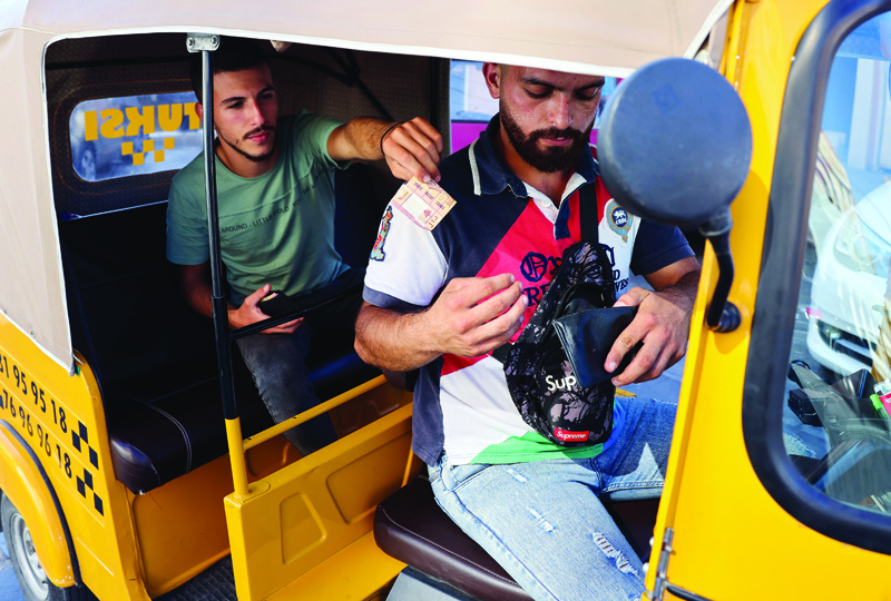 BATROUN: A passenger pays a tuktuk taxi drivers as he arrives to destination in the Lebanese city of Batroun north of the capital.-AFPnn