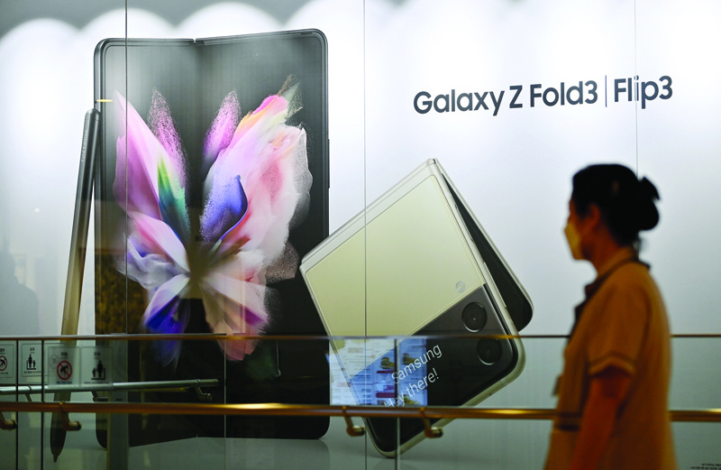 SEOUL: A woman walks past an advertisement for the Samsung Galaxy Z Fold3 and Flip3 smartphones at the company's Seocho building in Seoul yesterday. - AFPn