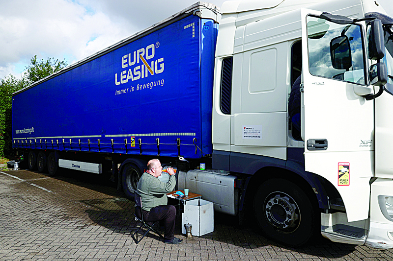 ASHFORD, US: A driver eats a meal beside his lorry at Ashford International truck stop, in Ashford, south-east England on Tuesday. Sat at a truck stop between London and the Channel Tunnel, Dean Arney, who has worked as an HGV diver for 40 years sees little to recommend the work. - AFPnn