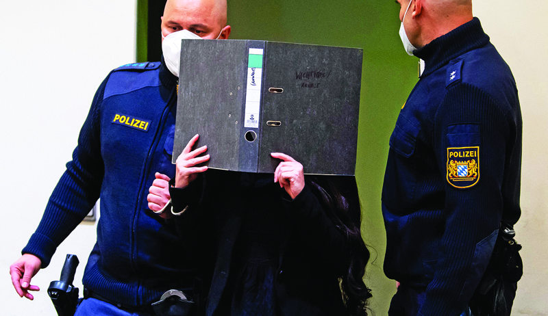 MUNICH: Jennifer W (center), a German woman who joined the Islamic State jihadist group, hides her face behind a folder as she arrives at court for the verdict of her trial in Munich yesterday. – AFP n