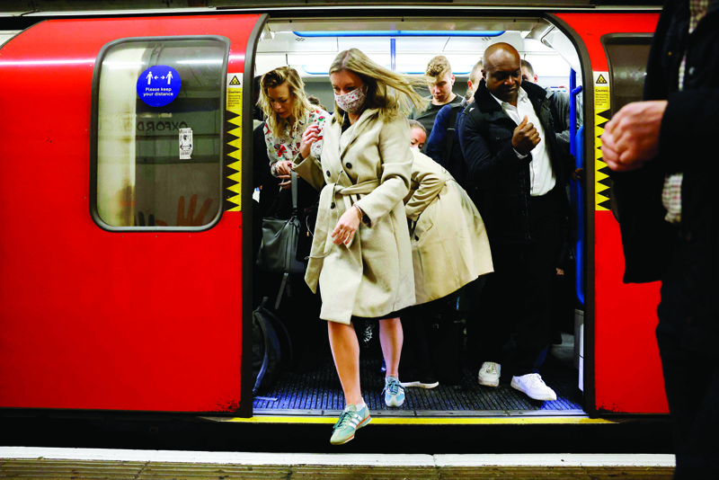 LONDON: Commuters, some wearing face coverings to help prevent the spread of coronavirus, walk out of a Transport for London (TfL) underground train in London yesterday. - AFP n