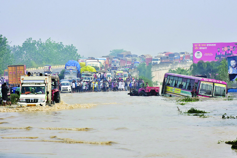 RAMPUR, India: Commuters stand on a flyover on a flooded national highway after the river Kosi overflowed following heavy rains in Uttar Pradesh state yesterday. - AFP n
