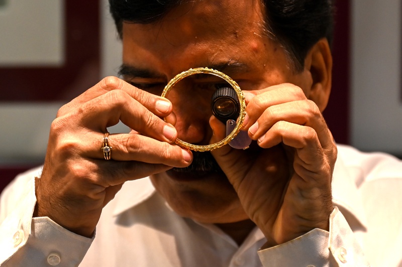 MUMBAI: A shop manager examines a gold bracelet at a jewelry shop on Aug 11, 2021. - AFP n