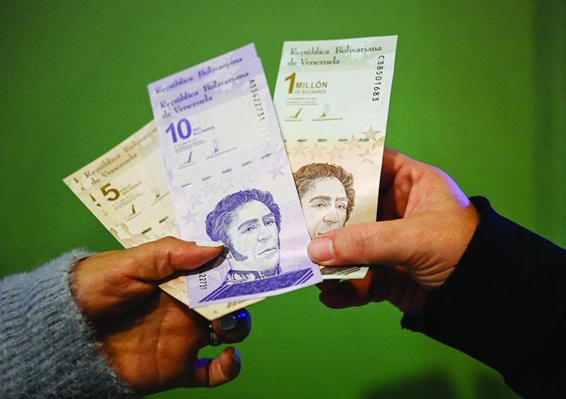 CARACAS: People show new five and ten bolivar banknotes and another of one million bolivars that will continue to circulate with a value of one bolivar, after making a cash withdrawal at an ATM on Friday. - AFP n