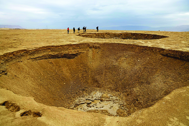 Hikers walk next to sinkholes across a dried-up sea area which exposed and created a salt plain, some 20 Km south of the Israeli Kibbutz Ein Gedi in the southern part of the Dead Sea, on January 15, 2021. – AFP photosnn