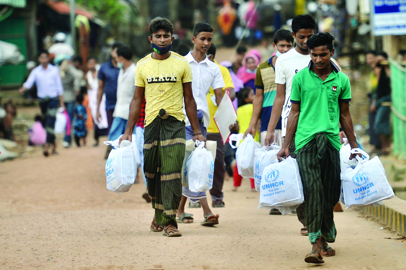 UKHIA: Rohingya refugees walk back home after collecting relief material at the Kutupalong refugee camp in Ukhia yesterday. - AFPnn