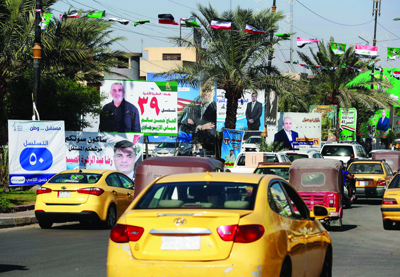 BAGHDAD: Cars drive in front of electoral billboards of candidates for the upcoming parliamentary elections, in the Iraqi capital Baghdad's Sadr City neighborhood. - AFP n