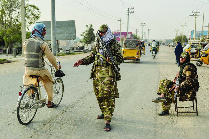 KUNDUZ: Taleban fighters check commuters along a road in Kunduz yesterday. - AFP n