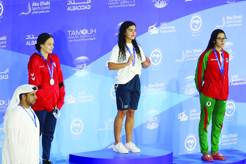 ABU DHABI: Kuwait's Lara Dashti (center) stands on the podium after winning the gold medal in the 25 meters race at the Arab Swimming Championship yesterday. - KUNAnnn
