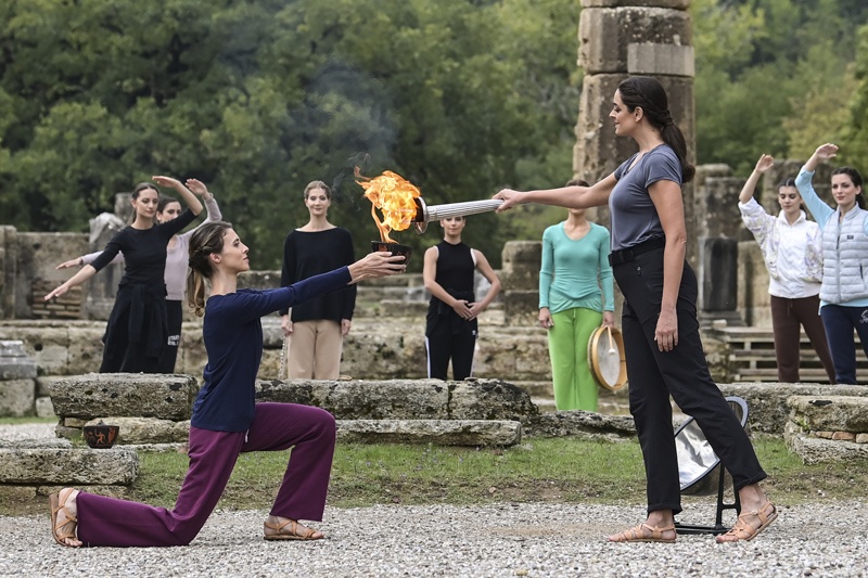 OLYMPIA: Greek actress Xanthi Georgiou (right), playing the role of the High Priestess, lights up the torch during the last rehearsal of the flame lighting ceremony for the Beijing 2022 Winter Olympics at the Ancient Olympia archeological site, birthplace of the ancient Olympics in southern Greece yesterday. - AFPn