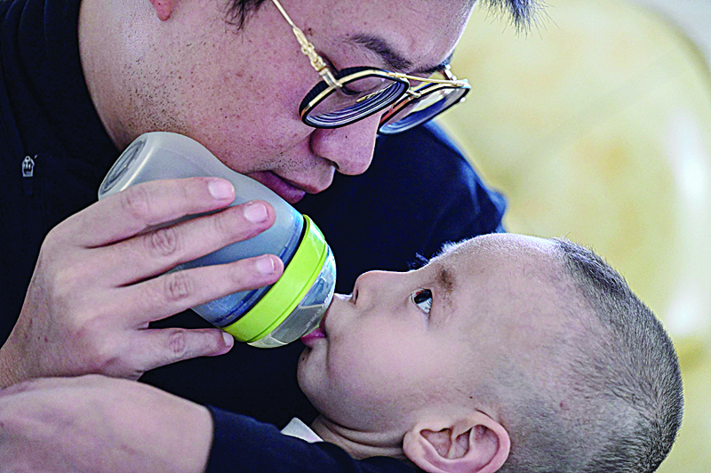 Photo shows Xu Wei feeding his son Xu Haoyang, who was diagnosed with Menkes syndrome, with honey water at home in Kunming in southwestern China's Yunnan province.-AFP photosn