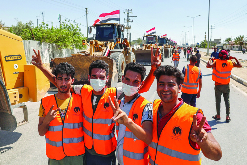 RAFAH: File photo shows Egyptian workers pose for a photo by construction equipment provided by Egypt arriving at the Palestinian side of the Rafah border crossing between Egypt and the Palestinian Gaza Strip enclave. - AFPnnn
