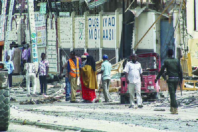 MOGADISHU: Police officers and people stand at the bomb explosion site in Mogadishu, Somalia, yesterday.-AFPn