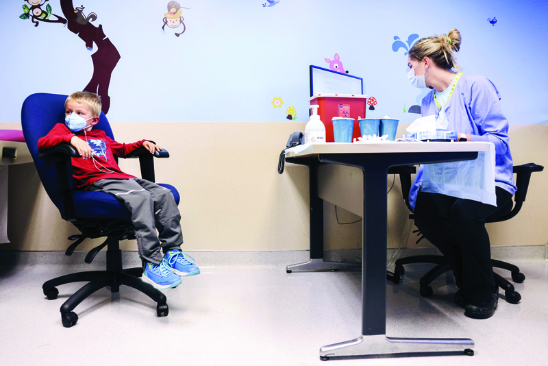 DENVER: Tyler Holm-Denoma, 5, left, waits for National Jewish Health registered nurse Emily Cole to give him a pediatric COVID-19 vaccine in Denver, Colorado. - AFP n