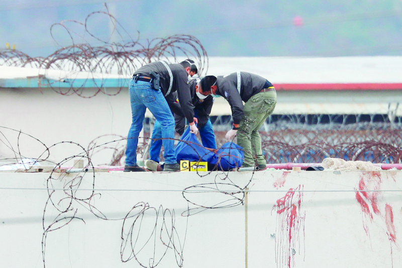 GUAYAQUIL: Members of the Ecuadorian police remove the body of an inmate on the roof of a pavilion of the Guayas 1 prison in Guayaquil, Ecuador. - AFP n