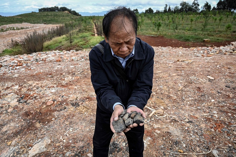 KUNMING: Environmental activist Zhang Zhengxiang holds rocks that he says are polluted at an area which used to be a cement factory construction site near Dian Lake in Kunming, in southwestern China's Yunnan province. - AFP n