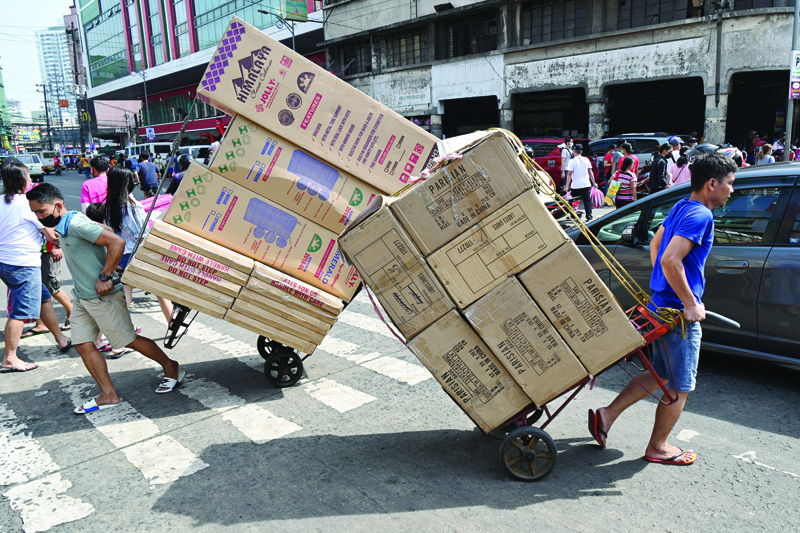 MANILA: Workers pull carts loaded with goods for delivery in the Divisoria district of Manila yesterday.-AFPn