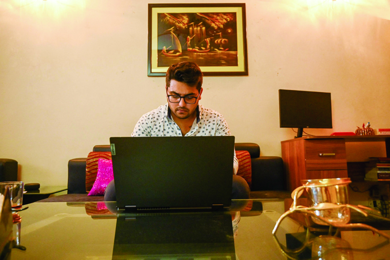 GHAZIABAD: This photo taken on October 5, 2021 shows 20-year-old college student Ishan Srivastava checking stocks online on his computer, while actively trading on apps on his smart phone, at his residence in Ghaziabad. - AFPn