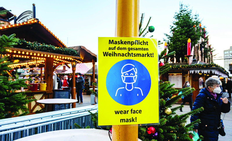 BERLIN: A sign requesting visitors to wear protective face masks is seen near booths of a Christmas market at Alexanderplatz in Berlin yesterday. - AFPnnn