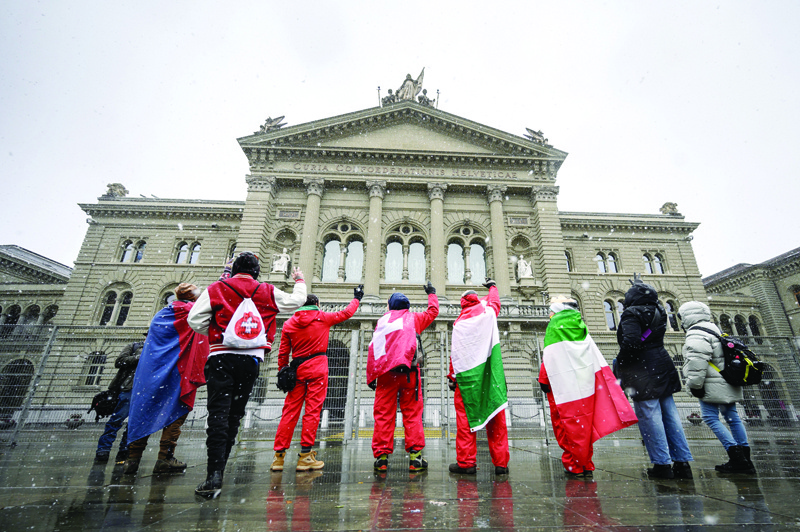 BERN, Switzerland: Protesters against the current measures to tackle the spread of the coronavirus demonstrate with national and Italian flags under the snow in front of the Swiss House Parliament following the result a nationwide vote on a COVID-19 law, in Bern yesterday. - AFPnn