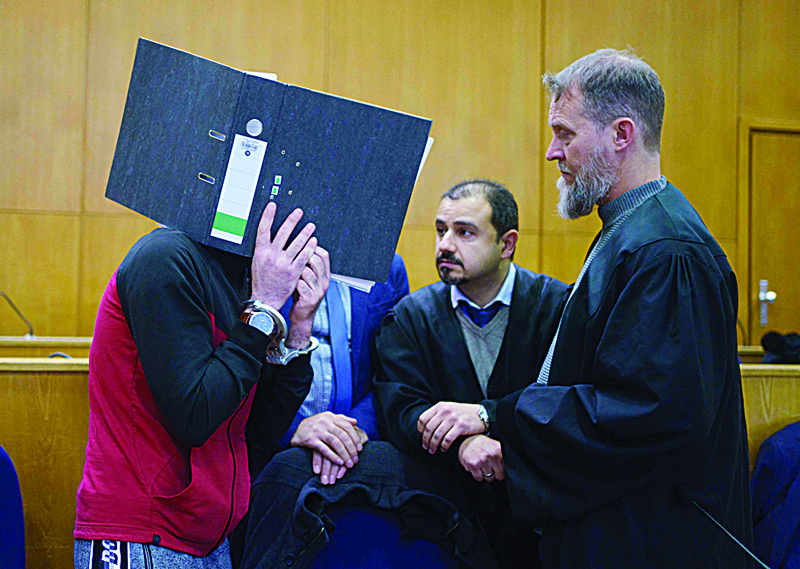 FRANKFURT, Hessen: The defendant Iraqi Taha Al-Jumailly (L) holds up a file to cover his face as he speaks with his lawyers Serkan Alkan (C) and Martin Heising (R) before the sentencing in his trial for charges of genocide. - AFPnnnn