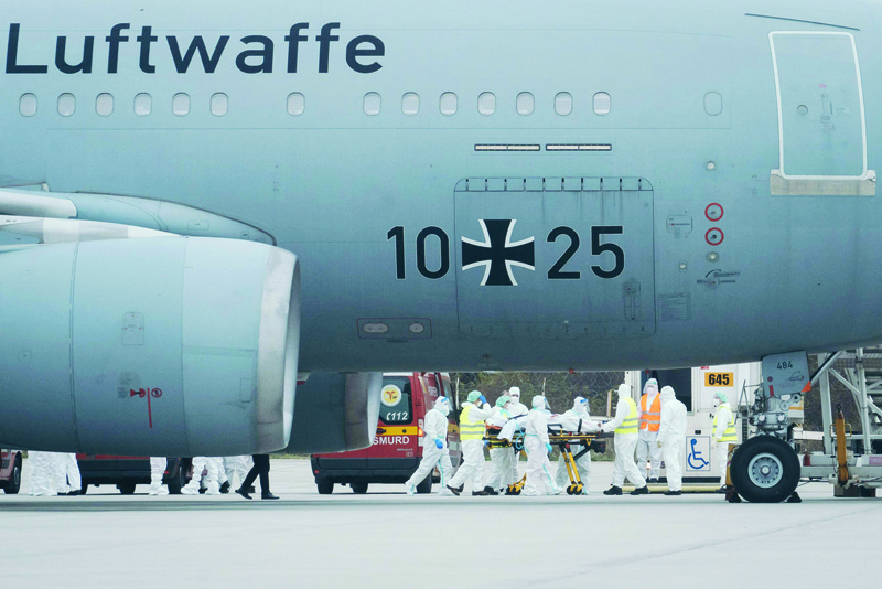 OTOPENI: Medical personnel help transfer a COVID-19 patient onto a German military airplane yesterday in Otopeni, Romania. Six Romanian patients with severe cases of COVID-19 have been transferred to Germany for treatment. - AFP n