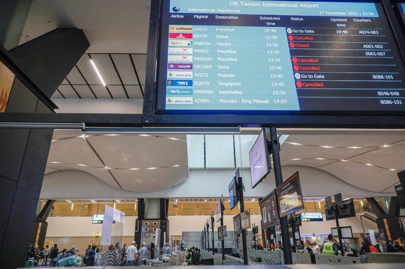 JOHANNESBURG: Airport staff assist travelers at various check-in counters while an electronic flight notice board displays some cancelled flights at OR Tambo International Airport in Johannesburg yesterday, after several countries banned flights from South Africa following the discovery of a new COVID-19 variant Omicron. - AFP n