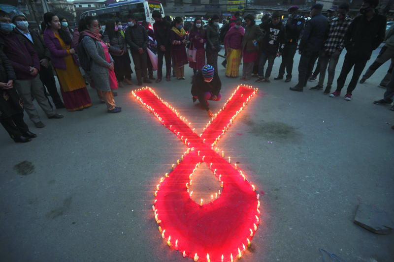 KATHMANDU: A volunteer lights candles forming the shape of a red ribbon during an awareness event organized on the eve of the World AIDS Day in Kathmandu, Nepal yesterday. - AFPn