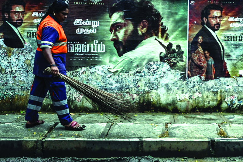 A sanitation worker walks past a poster of actor Suriya Sivakumar from the movie Jai Bhim in Chennai on November.-AFP n