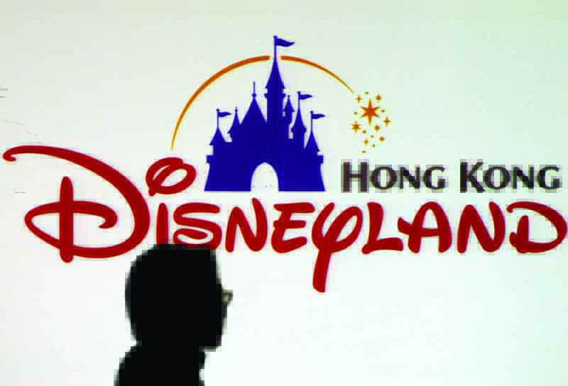 In this file photo a journalist stands in front of a Walt Disney's Hong Kong theme park logo prior to a press conference in Hong Kong.-AFP n