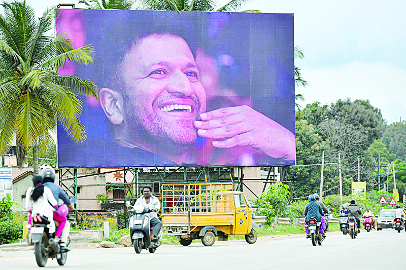 In this file photo commuters drive past a poster of late Indian film star Puneeth Rajkumar in Bangalore.-AFP photosn
