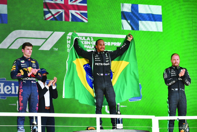 SAO PAULO: Mercedes' British driver Lewis Hamilton (center), Red Bull's Dutch driver Max Verstappen (left) and Mercedes' Finnish driver Valtteri Bottas celebrate on the podium after obtaining the first, second and third positions respectively, in Brazil's Formula One Sao Paulo Grand Prix at the Autodromo Jose Carlos Pace, or Interlagos racetrack, in Sao Paulo, on Sunday. - AFPn