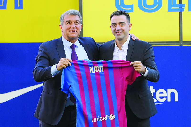 BARCELONA: Newly-appointed FC Barcelona's Spanish coach Xavi Hernandez (right), flanked by FC Barcelona's Spanish president Joan Laporta, poses with his jersey during the presentation ceremony at the Camp Nou stadium in Barcelona yesterday. - AFPnn