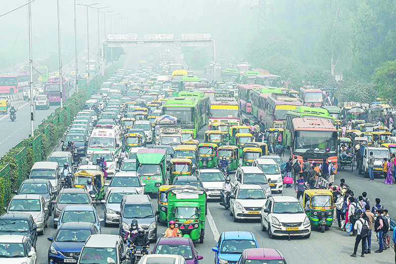NEW DELHI: Commuters make their way along a busy road under heavy smoggy conditions in New Delhi. — AFP