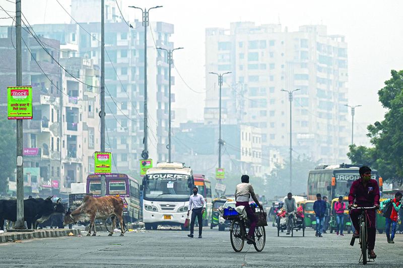 NEW DELHI: Commuters make their way amid smoggy conditions in New Delhi yesterday. – AFP n
