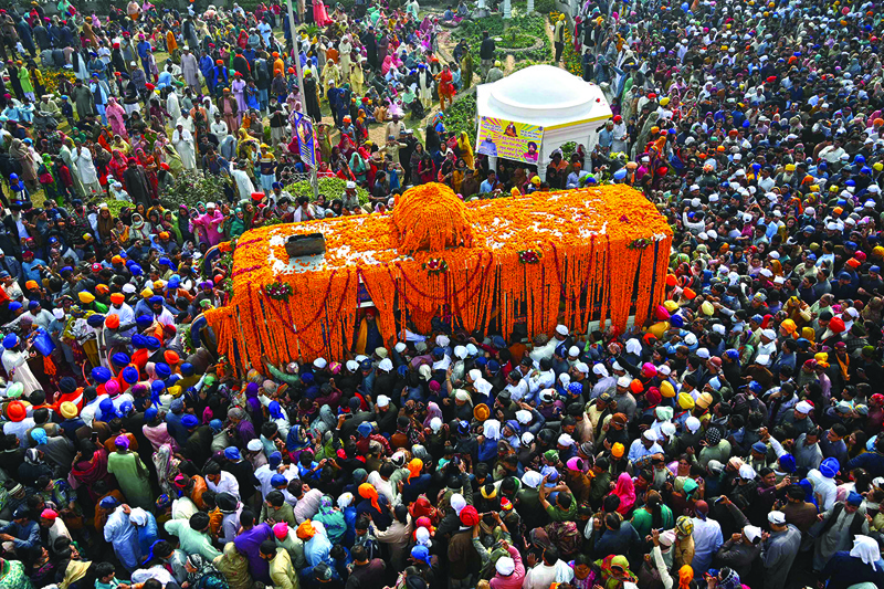 PUNJAB PROVINCE: Sikh devotees gather around a bus carrying the Guru Granth Sahib (Sikh holy book) during a religious procession on the occasion of the birth anniversary of Guru Nanak Dev, the founder of Sikhism, in Nankana Sahib. - AFP n
