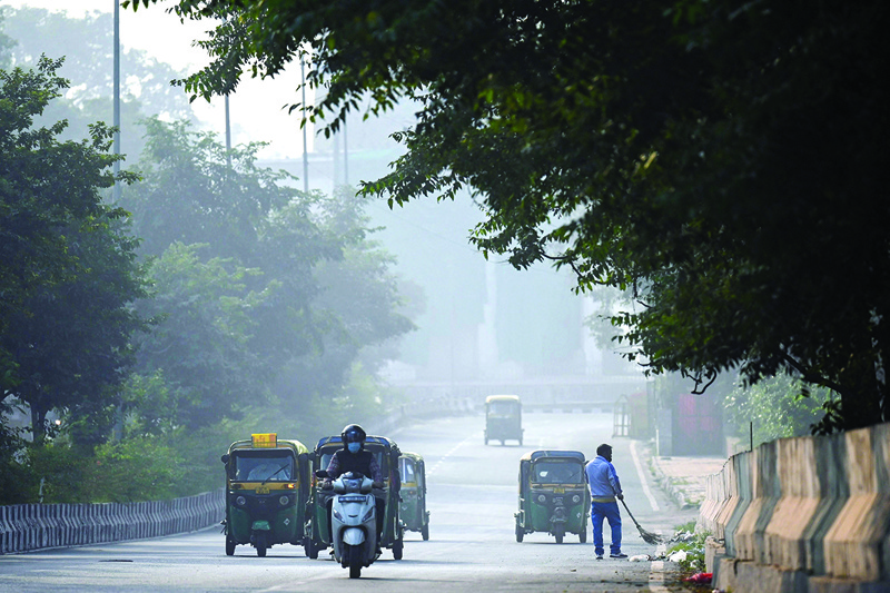 NEW DELHI: Commuters make their way along a street amid heavy smoggy conditions in New Delhi yesterday. - AFPn