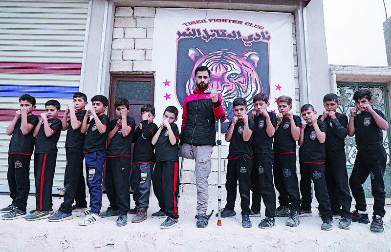 Fadel Othman, a Syrian 24-year-old amputee kung-fu teacher, and his young students pose for a picture outside his martial arts school in the rebel-held town of Abzimu in the western countryside of Aleppo province.-AFP photosn