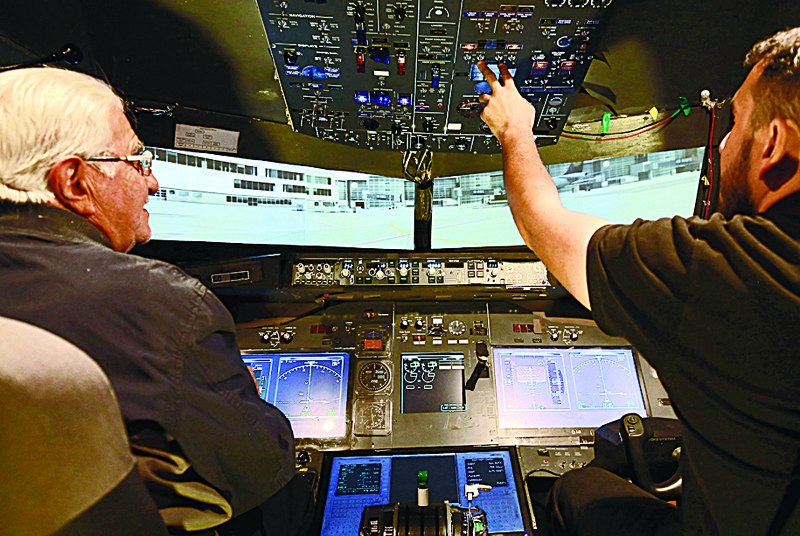 nMuhammad Malhas (left), 76, sits at his flight simulator cockpit. - AFP photosn