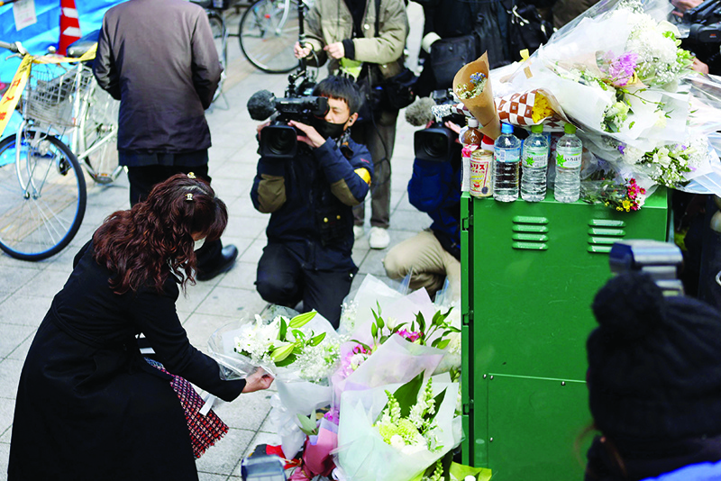 OSAKA, Japan: A woman offers flowers for victims in front of an office building, where a fire broke out the previous day, in Osaka yesterday. —AFP