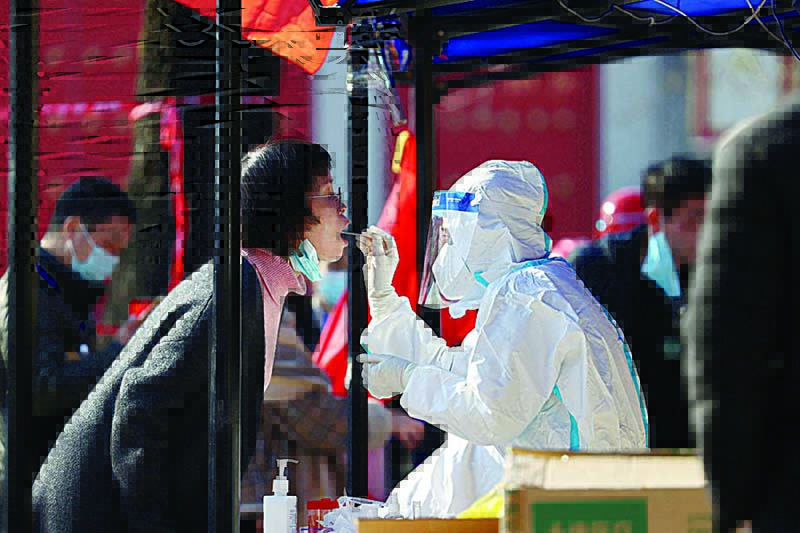 XIAN, SHAANXI, China: A medical worker takes a sample from a resident to be tested for the COVID-19 coronavirus in Xi’an, in China’s northern Shaanxi province yesterday, after the detection of more than 40 new cases raised concerns of wider transmission ahead of a busy travel season. —AFP