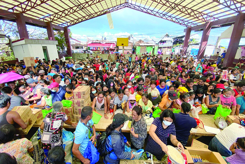 SURIGAO CITY, Philippines: In this handout photo taken on December 20, 2021 and received from Greenpeace yesterday, residents queue up to receive relief goods at a village in Surigao city, surigao del norte province, days after super Typhoon Rai devastated the city. —AFP
