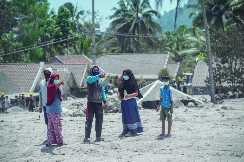 LUMAJANG, East Java, Indonesia: Family members wait for news as rescuers search for victims at the buried homes in Sumber Wuluh village in Lumajang yesterday, following the Mount Semeru eruption that killed at least 34 people. - AFPnn