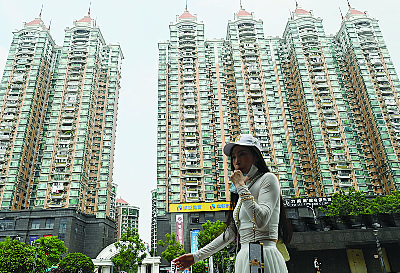 GUANGZHOU, China: This file photo taken on September 17, 2021 shows a woman walking past a housing complex by Chinese property developer Evergrande in Guangzhou, China's southern Guangdong province. --  AFPn