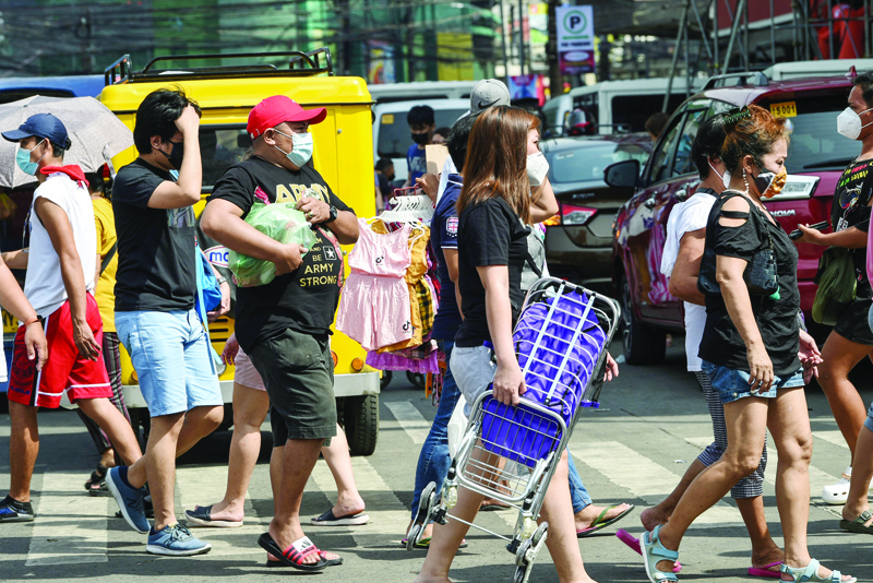 MANILA: People cross a street to shop in the Divisoria district of Manila on Tuesday.-AFPn